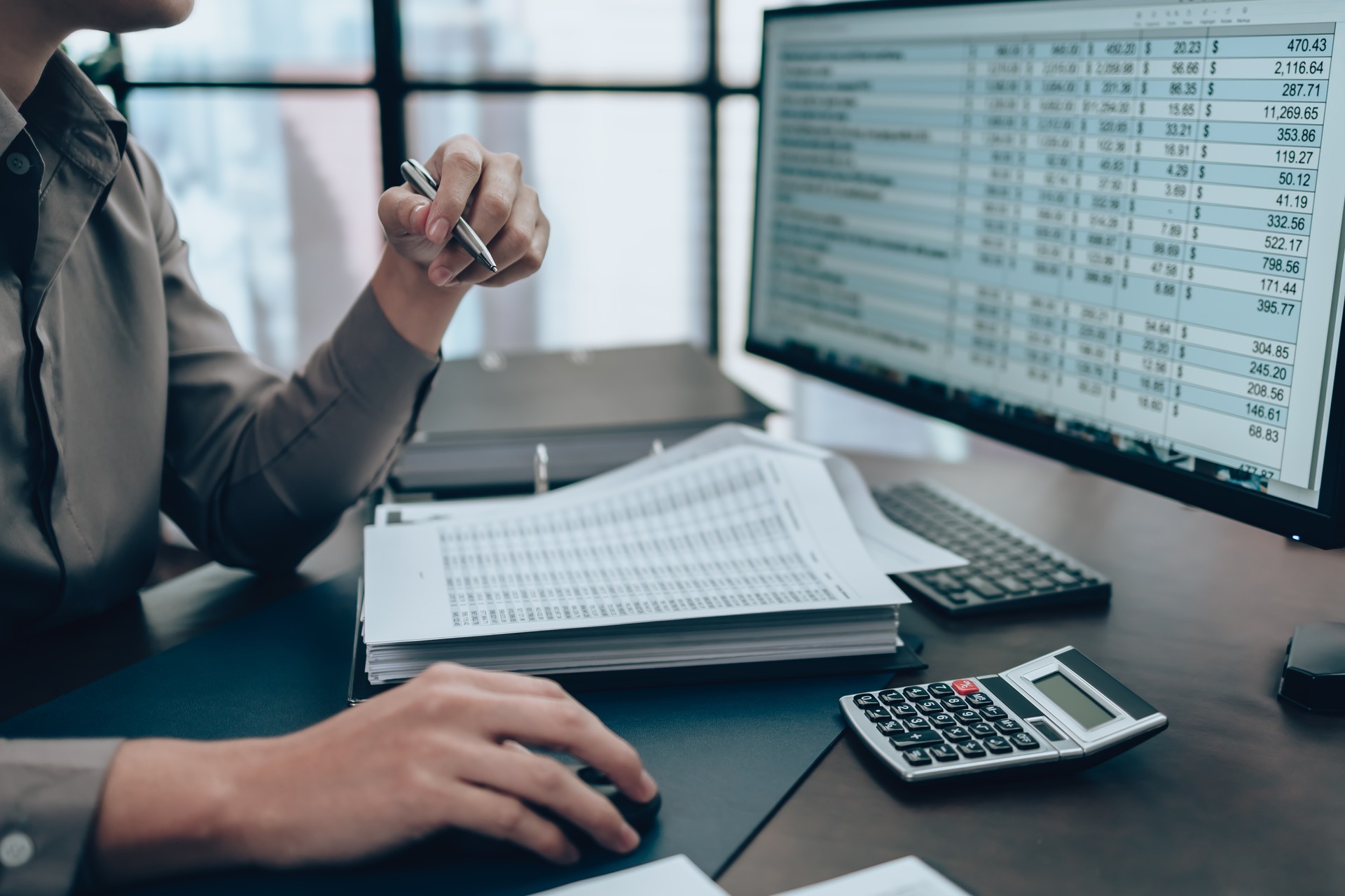 Investors working on desk office and check data cost, balance, profit and  currency on monitor screen. Accounting and  Financial concept.